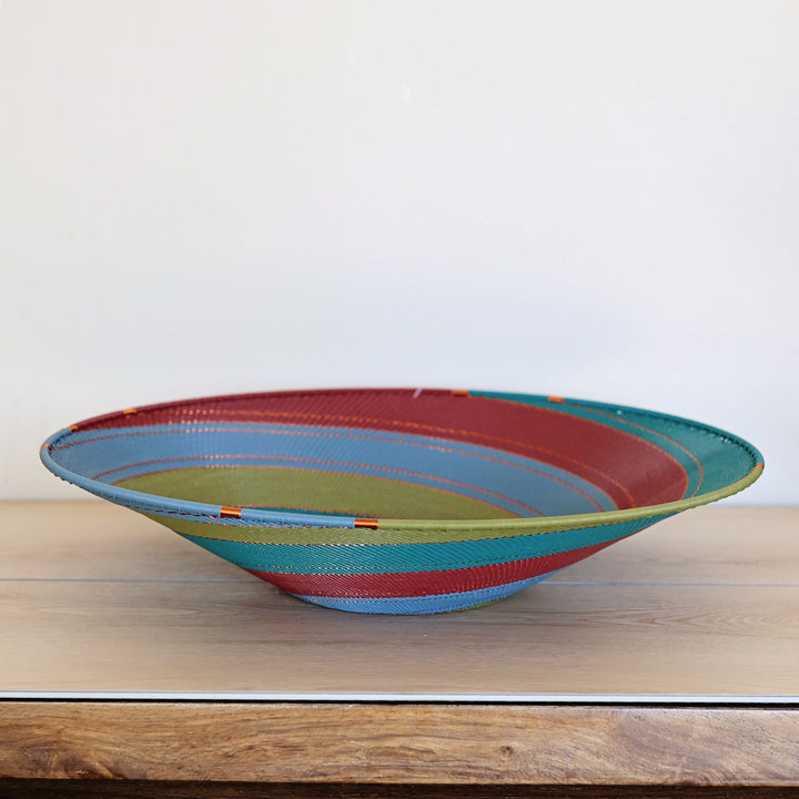 Tidepool Zulu Extra Large Shallow Basket handwoven in South Africa with teal, deep green, and warm red in a diagonal stripe pattern.