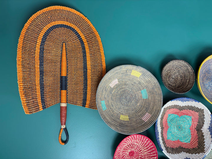 Fair trade vetiver grass fan with leather handle handmade by artisans in Ghana, perfect for wall decor.