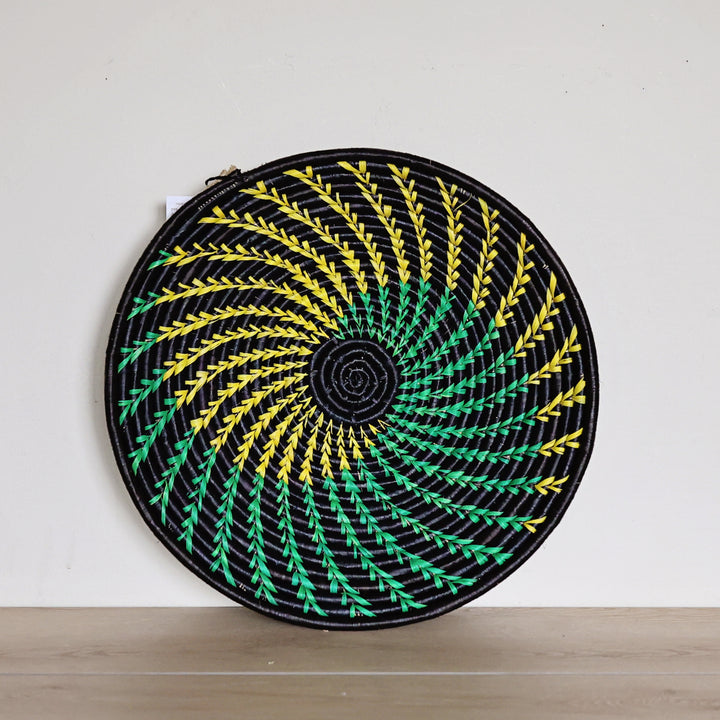 Yellow, green and black raffia fruit basket handwoven by African artisans in a bold radiating pattern.